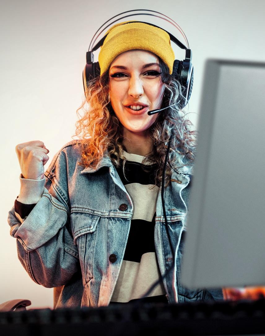 Junge Frau zockt am Laptop und ballt vor Freude die Faust