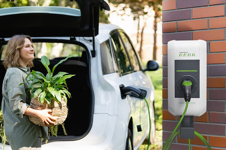 Frau bringt Einkäufe ins Haus. Im Vordergrund sieht man ihre installierte Wallbox.