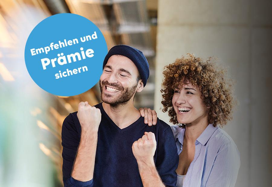 Eine Mann ballt die Faust und freut sich, eine Frau legt die Hand auf seine Schulter und lacht ebenfalls