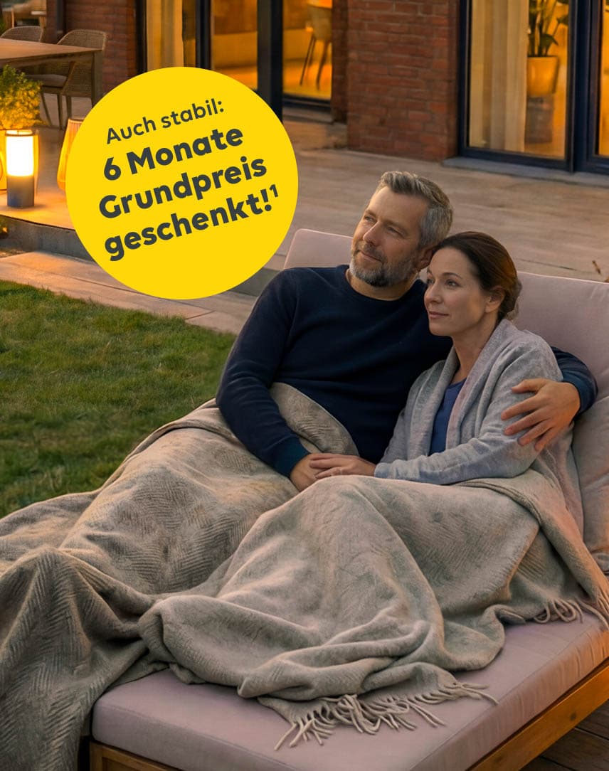 Ein Paar liegt auf einer Liege vor dem erleuchteten Haus