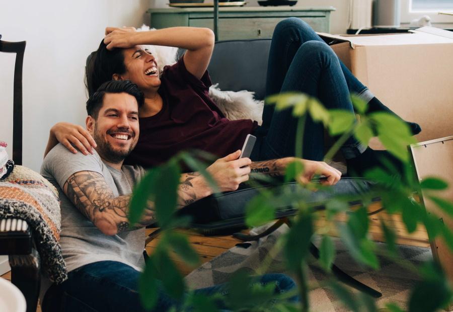 Junges Paar freut sich inmitten von Umzugskartons über den Einzug in sein neues Zuhause