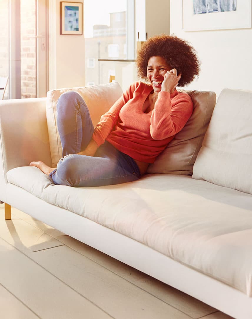 Frau telefoniert mit dem Smartphone auf dem Sofa