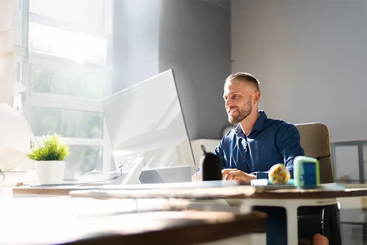 Mann schaut zufrieden auf Computerbildschirm