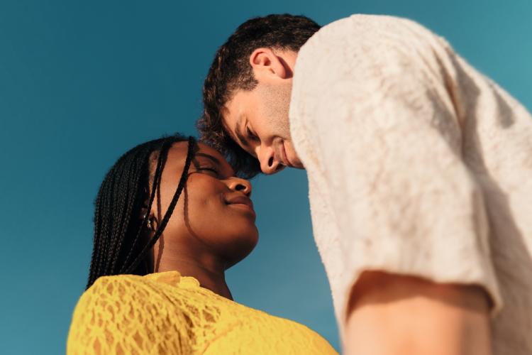 Ein Paar schaut sich vor blauem Himmel verliebt an